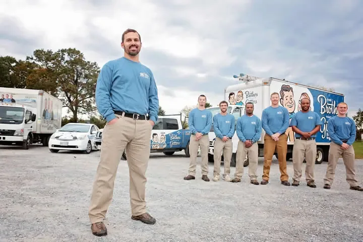 The Brothers That Just Do Gutters franchise team of 7 uniformed professionals with franchise owner in front of branded service truck